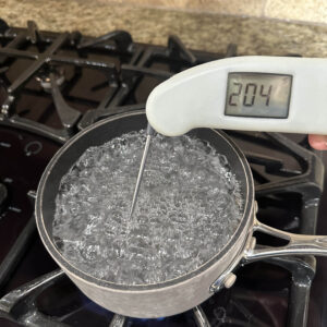 Thermometer in boiling water with 204 degrees on digital screen