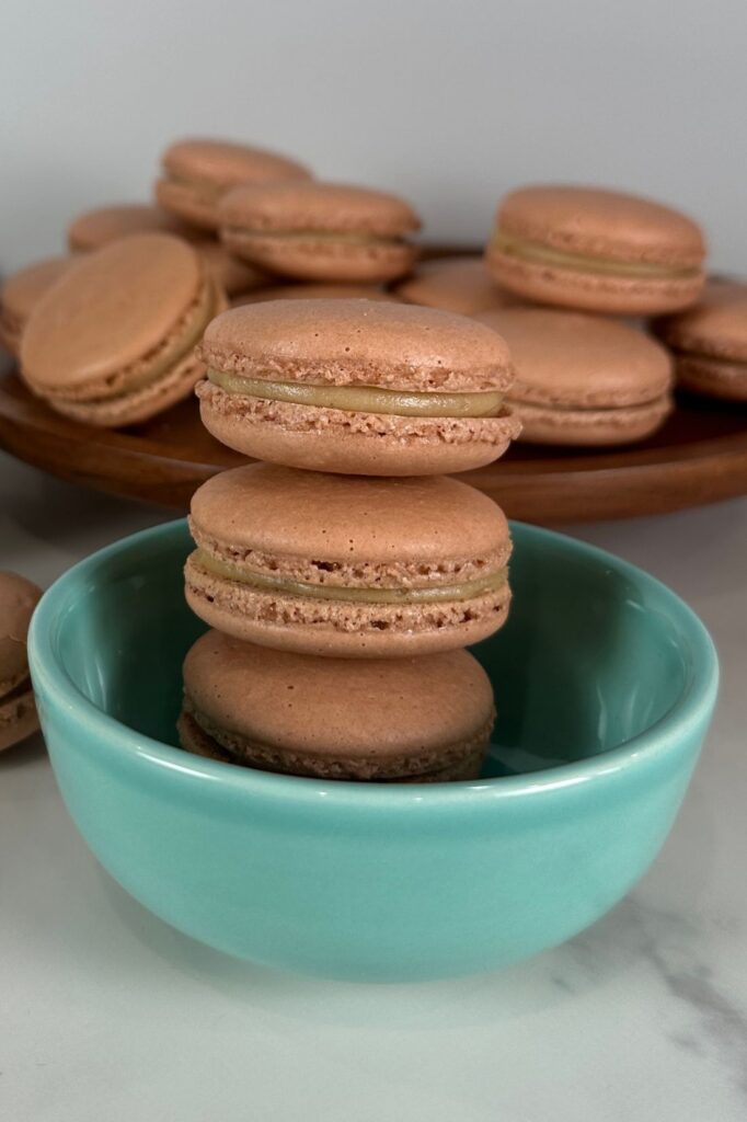 Salted Caramel Macarons stacked in a cute teal bowl.